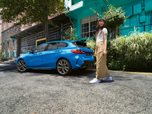 Bilde av en ung kvinne med en BMW 1-serie i fargerike omgivelser