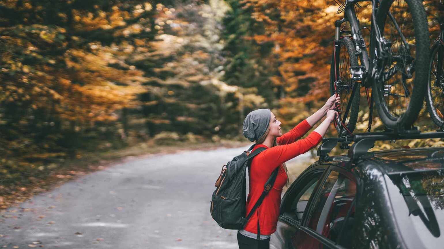 Bilde av kvinne som fester sykkelen i takstativ på bilen Bilde av kvinne som fester sykkelen i takstativ på bilen