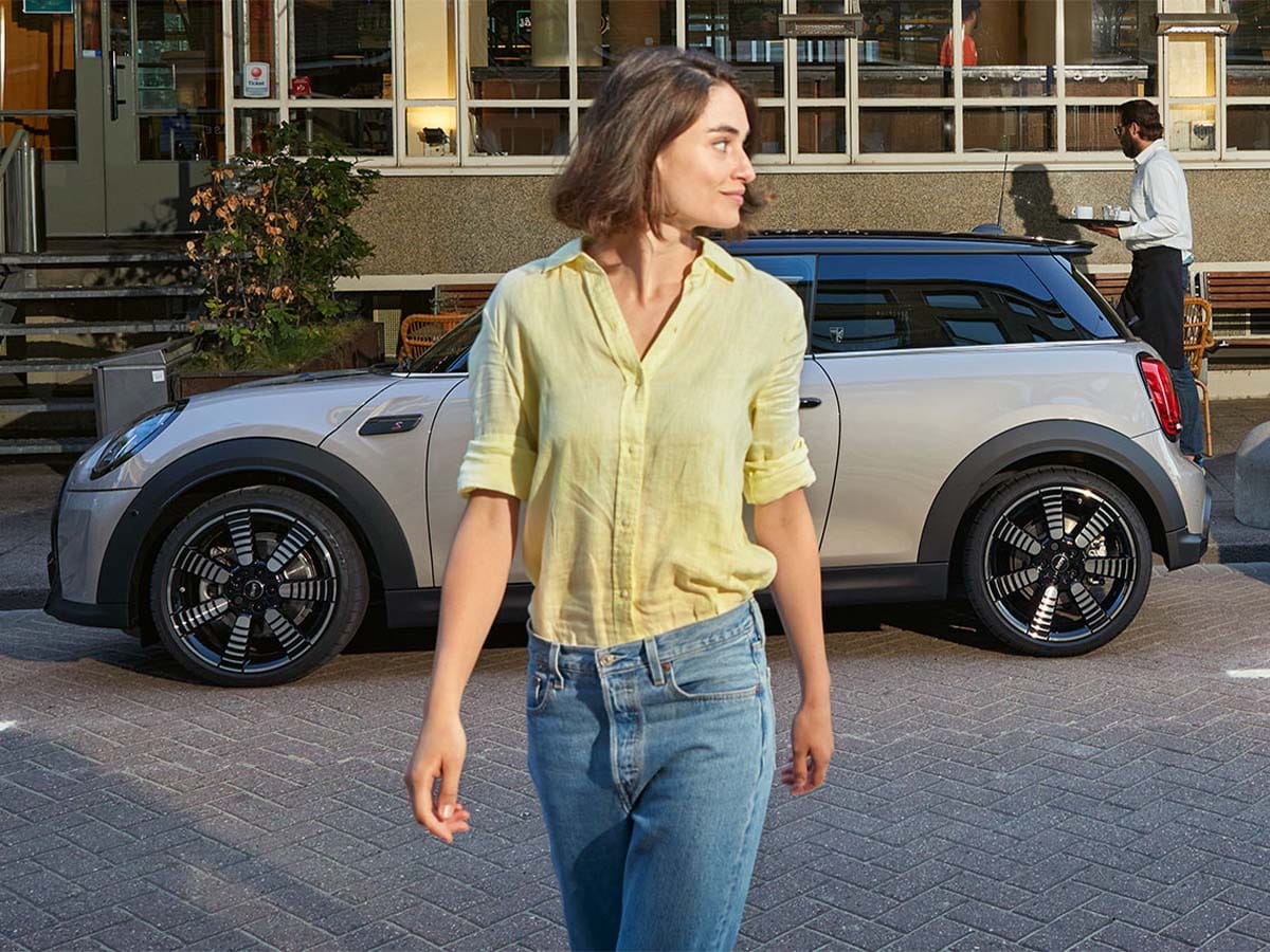Kvinne og en MINI Cooper som har parkert utenfor en kafé
