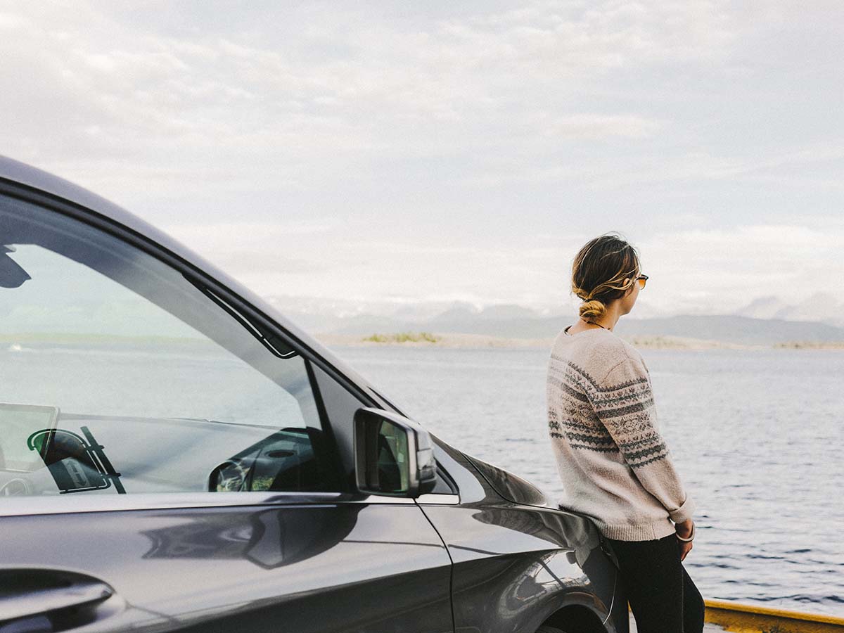 Kvinne ved bilen ved havet